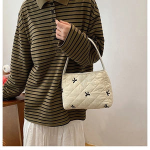 Détail du sac seau matelassé crème avec broderies de nœuds noirs et motif à carreaux