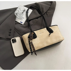 Close-up of a two-tone suede tote bag with contrast leather trim and chic strap detail