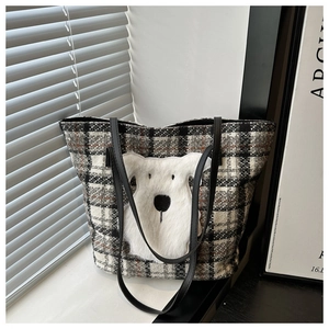 Detail of tweed checkered tote bag featuring a fluffy white dog patch and black leather strap