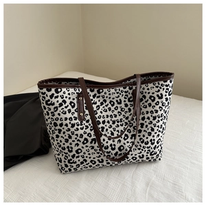 Detail of leopard print tote bag featuring brown leather trim and metallic rivets