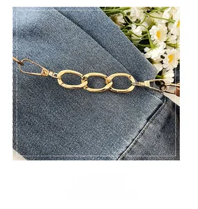 Close-up of polished gold metal chain strap with lobster clasps on denim background