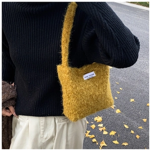 Gros plan du sac bandoulière en peluche jaune gingembre avec étiquette tissée blanche
