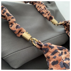Detail of leopard print fabric strap with polished gold-tone metal hardware and ring