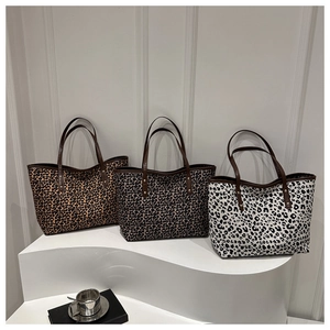 Three leopard print tote bags in classic, gray and monochrome patterns on a stand