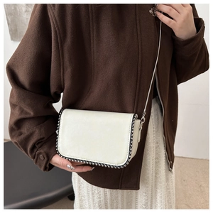 Close-up of cream leather crossbody bag with chain strap and silver ball trim