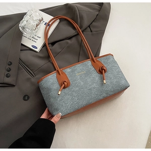 Detail view of the textured grey wool tote with brown leather handles and knot accents