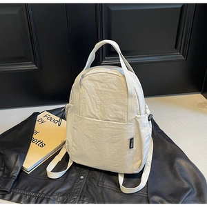 Gros plan du sac en nylon beige montrant la texture plissée et l'étiquette YCYNINE