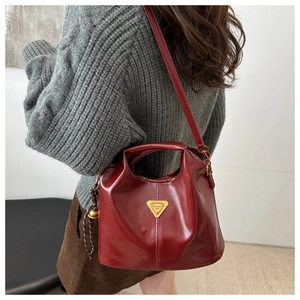 Detailed back view of a burgundy leather bucket bag with golden triangle logo worn by model