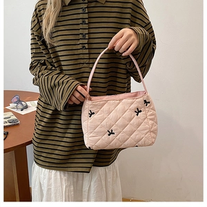 Détail du sac fourre-tout matelassé rose clair avec nœuds noirs et texture moelleuse