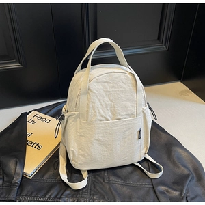 Gros plan du sac à dos en nylon blanc crème avec texture plissée sur cuir noir