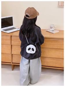 Detail showing the back of a cute plush panda crossbody bag worn by a girl