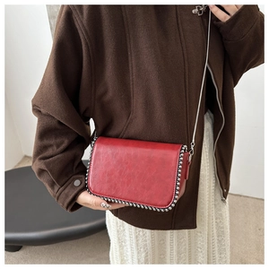 Close-up of red retro chain bag featuring silver rivet trim and smooth faux leather texture