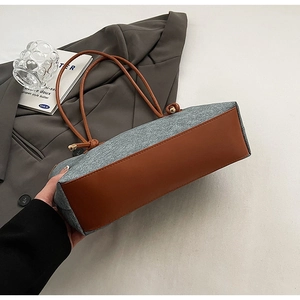 Detail of wool felt and brown leather patchwork tote bag on a gray suit jacket