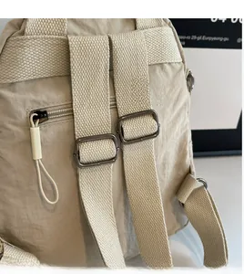 Detail view of beige nylon backpack with adjustable shoulder straps and anti-theft back pocket