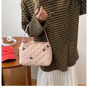Gros plan d'un sac seau matelassé rose avec broderies de petits nœuds noirs élégants