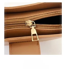 Detailed close-up of premium golden metal zipper and smooth brown leather on handbag