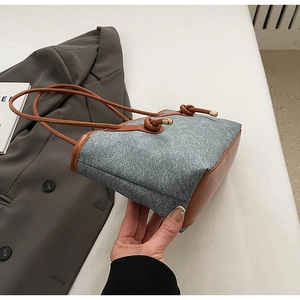 Detail of blue textured fabric tote bag with brown leather trim and knotted straps