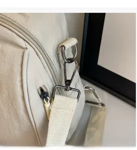 Detail of high-quality dark grey metal hardware and zipper on a beige nylon backpack