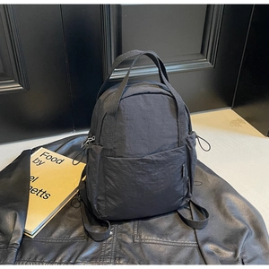 Détail du sac à dos en nylon noir avec tissu résistant et poches latérales à cordon pratiques