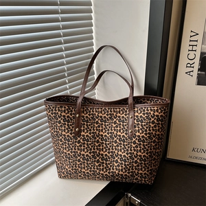 Leopard print tote bag with brown leather handles placed by a window in a stylish room