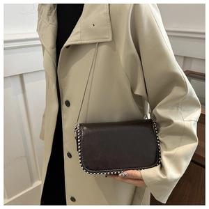 Detail of dark brown chain crossbody bag with silver rivet studs and glossy finish
