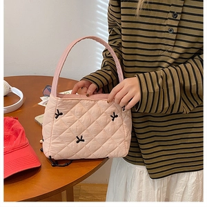 Détail du sac fourre-tout matelassé rose avec broderie nœud noir et texture gonflée