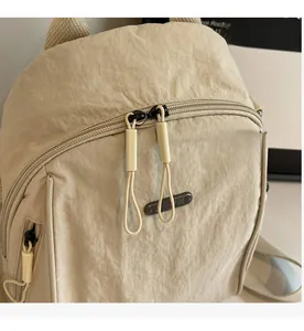 Detail of beige nylon backpack showing dual zipper closure and textured fabric surface