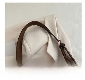 Close-up of dark brown leather shoulder strap with gold buckle and neat stitching details