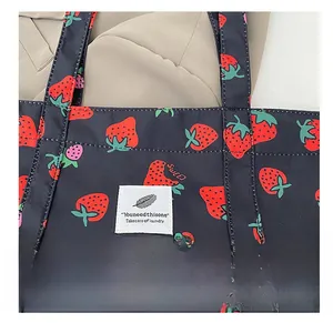 Detail of strawberry print canvas tote bag featuring black base and white label tag