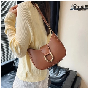 Brown retro half-moon underarm bag with gold horseshoe buckle worn by model