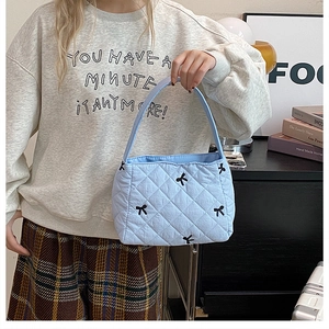 Détail du sac cabas matelassé bleu clair avec broderies de nœuds noirs et surpiqûres