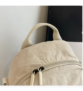 Detail view of water-resistant nylon backpack showing top handle and double zipper closure