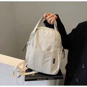 Détail du sac à dos en nylon beige avec poche latérale à cordon et poignée en sangle tissée