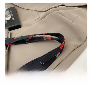 Close-up of wide black shoulder strap featuring vivid red strawberry prints on canvas