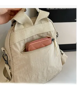 Detail of the anti-theft back zipper pocket on beige nylon backpack with small pink wallet