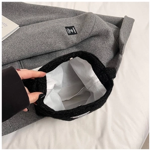 Détail du sac en tricot noir montrant la doublure blanche et le bouton pression