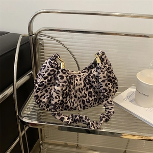 Detailed view of leopard print fabric texture and ruched handle on a stylish handbag