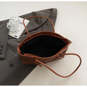 Top-view detail of caramel faux leather tote bag with gold logo and zip closure