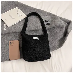 Détail du sac seau noir en peluche duveteuse avec écusson LOVE FASHION sur literie blanche