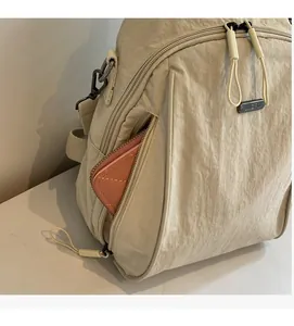 Detail view of the side zipper pocket on a beige nylon backpack showing storage capacity