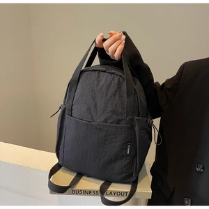 Détail d'un petit sac à dos en nylon noir avec poignée tissée et surface en tissu texturé