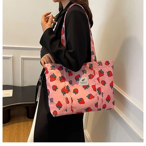 Detail showing the strawberry print pattern and woven label on this pink tote bag