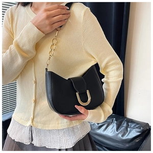 Detail of black crescent shoulder bag featuring gold U-shaped lock and chunky chain strap
