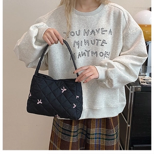 Gros plan sur un sac cabas matelassé noir avec broderies papillon roses et anses