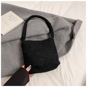 Détail du sac à main en peluche noire montrant la texture douce sur un manteau