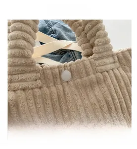 Detail view of beige corduroy tote with vertical texture and snap button closure