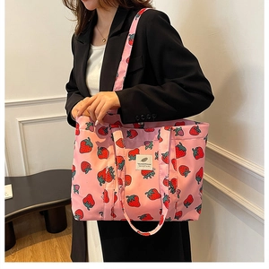 Detail of pink strawberry print tote bag featuring a white woven label and durable canvas