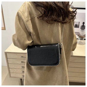 Detail showing the matte black leather texture and silver beaded trim on the flap of the bag