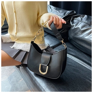 Detail of black crescent shoulder bag featuring gold U-shaped buckle and chain strap