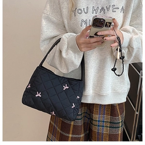 Détail du sac fourre-tout noir matelassé avec des broderies délicates de lapins roses
